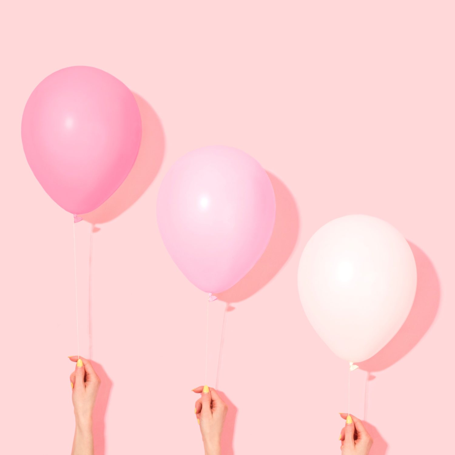 Three pink balloons against a pink background.